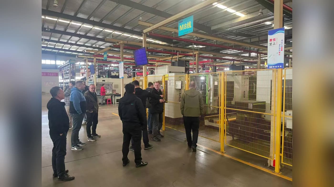 Buyers and hosts reviewing CNC machine tools inside a guarded machining workshop.