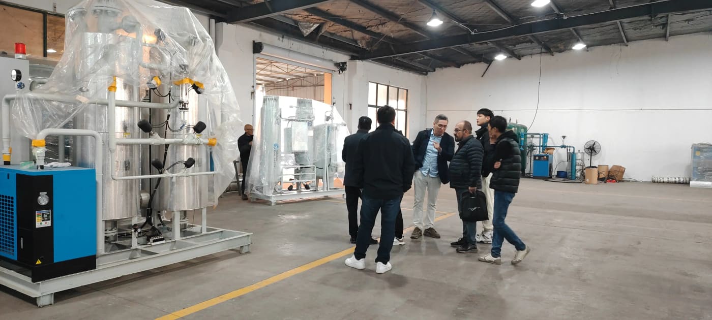 A supplier team walking buyers past newly built equipment wrapped for transport.